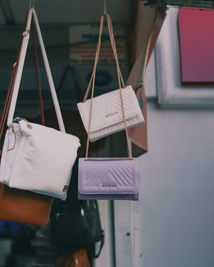 A collection of stylish leather handbags hanging in an outdoor market stall.