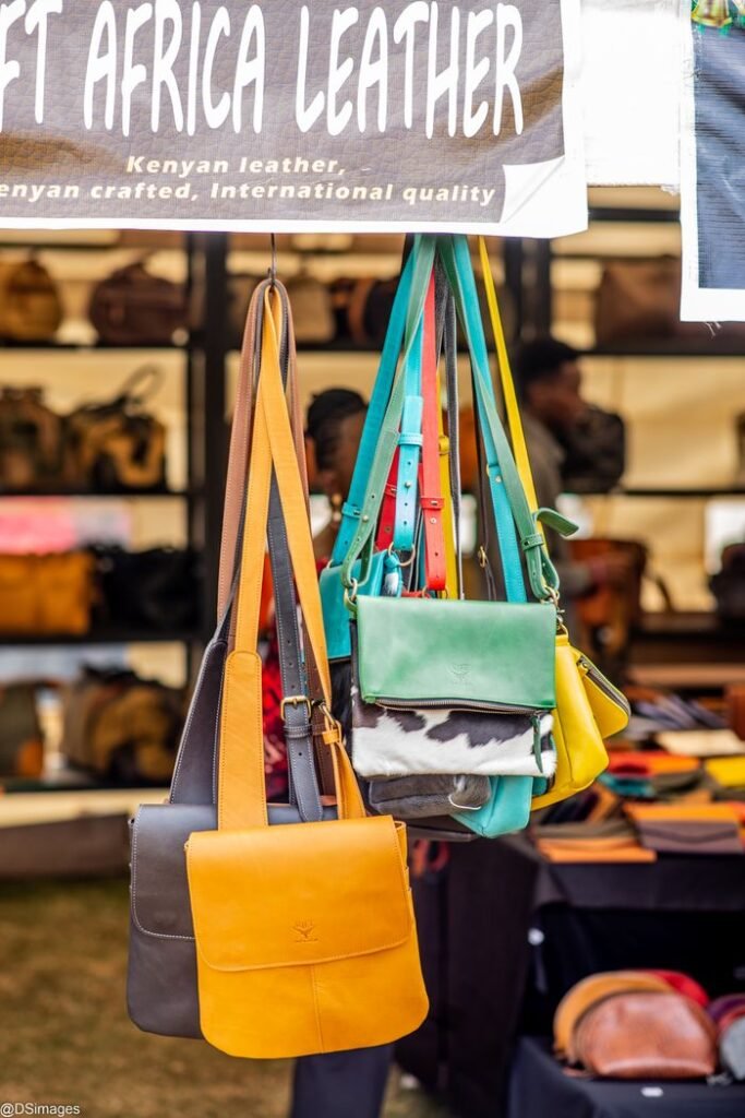Vibrant leather handbags hang at a Kenyan craft market, showcasing international quality and artistry.